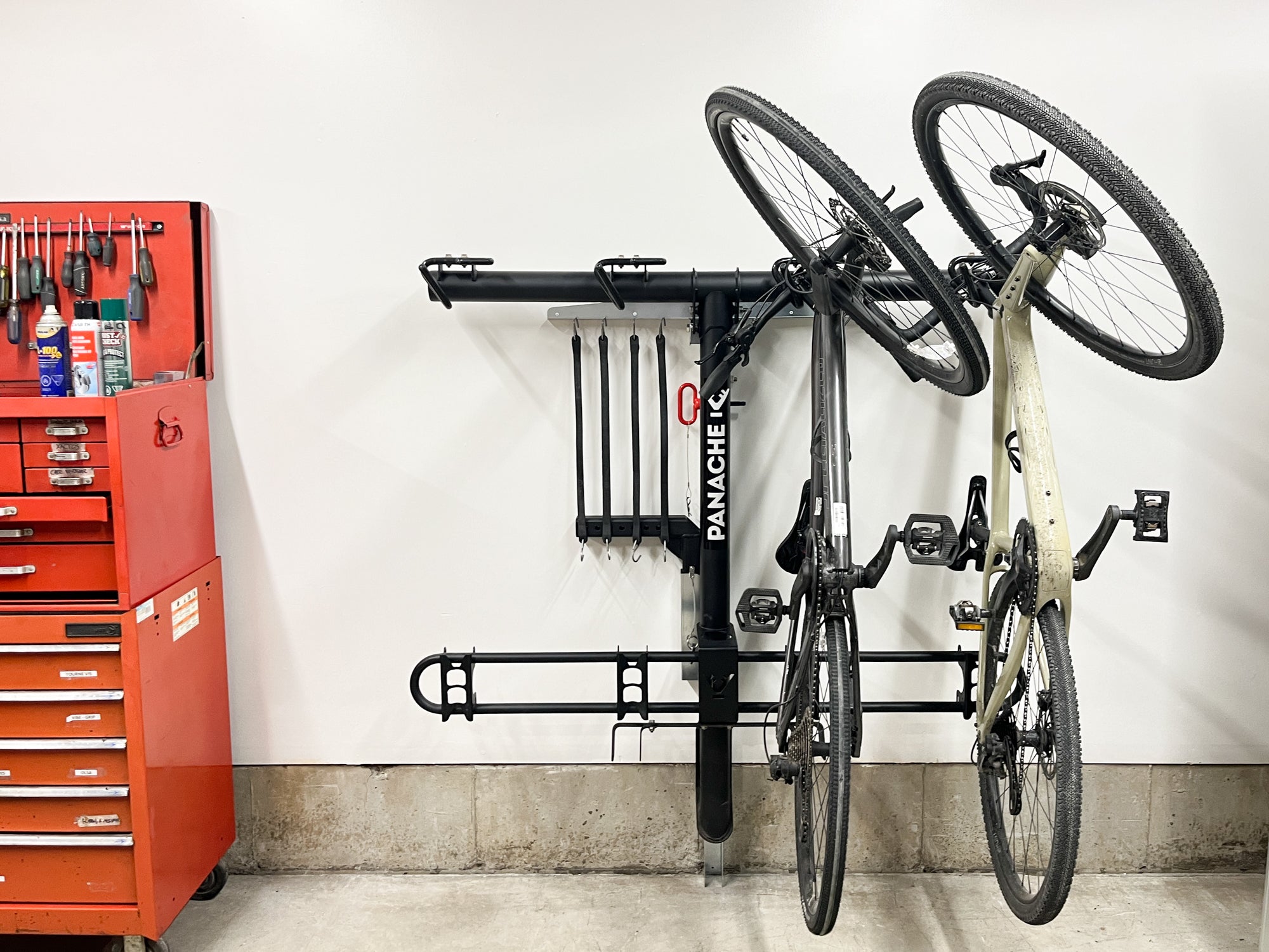 Panache rack wall mount installed on a garage wall with panache rack T4 rack stored on it with two bikes. You can also see that the mount provides a place for the mounting bolts, pin and adaptor.