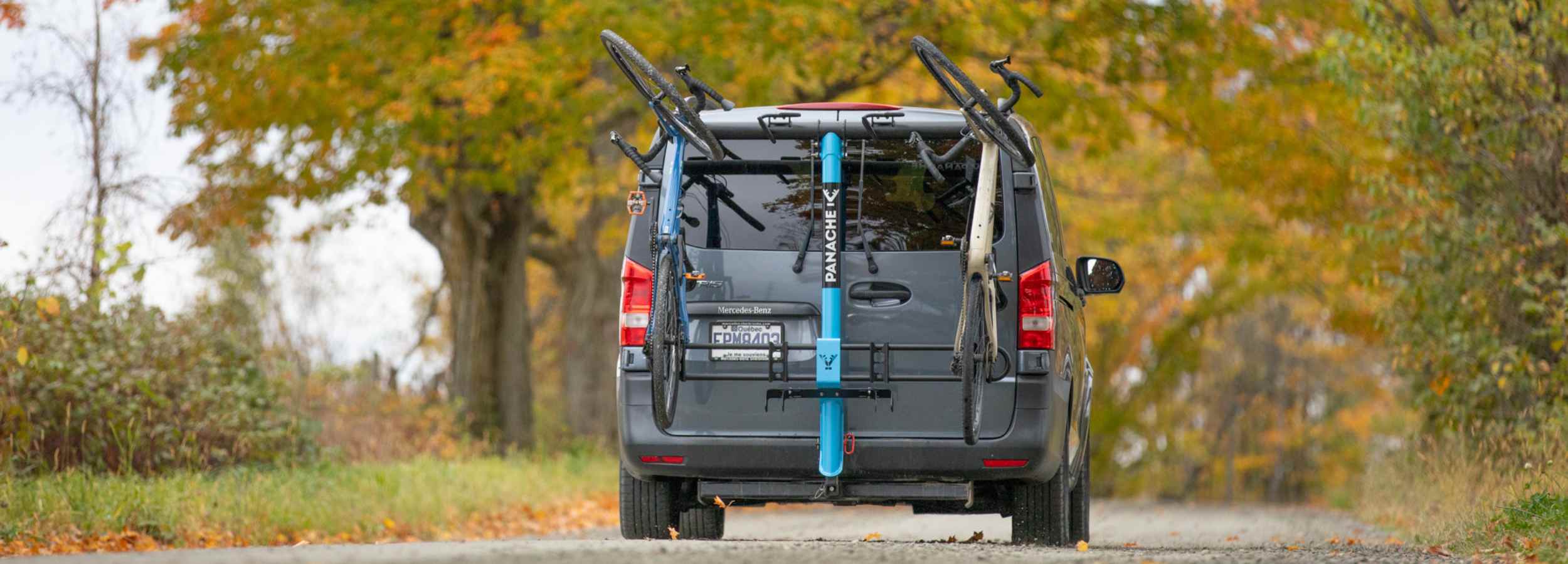 mini van équipé d'un porte-vélo Panache T4 roulant sur un chemin de campagne